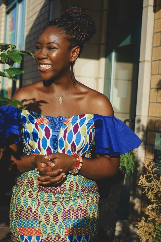 an african woman smiling with a blue top and green skirt