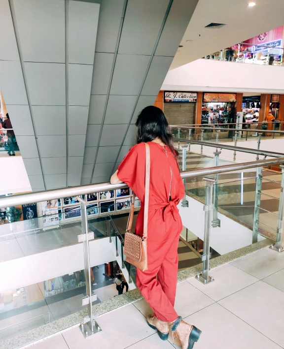 a woman in a red outfit is standing at a metal railing