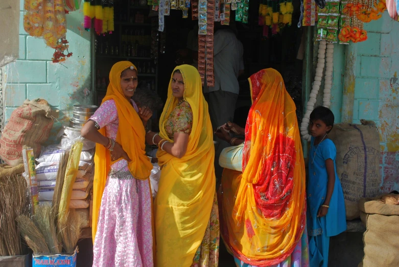 three women in brightly colored sari standing outside a shop