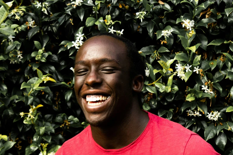 a man smiling in front of some bushes