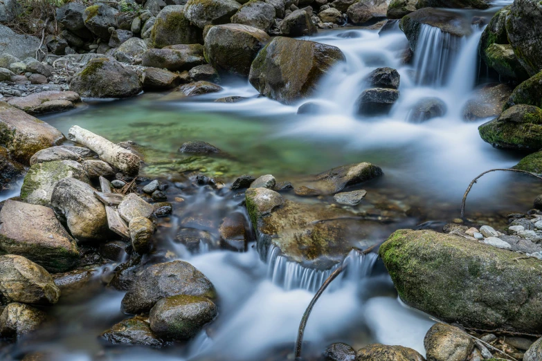 a stream flowing down a large rocks covered hillside