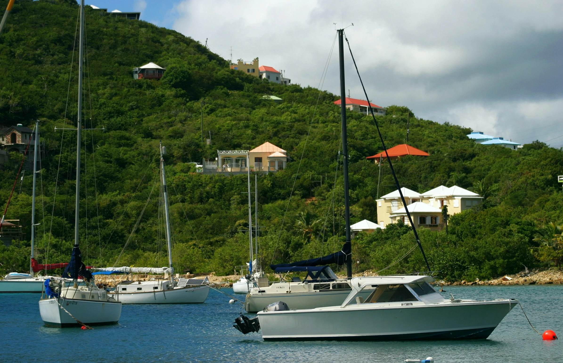 many boats are in the water near a cliff