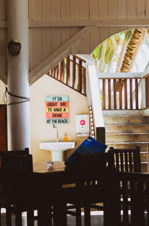 a house with two wooden chairs at a table and stairs to another room