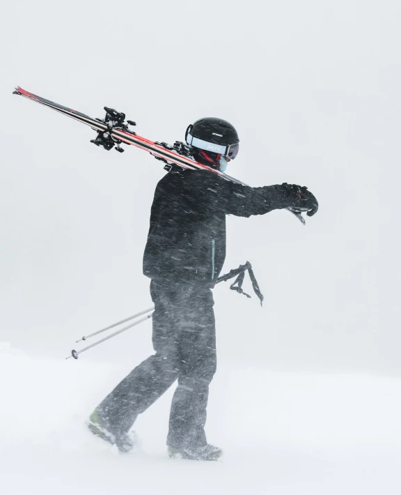 the skier is walking in the snow with skis strapped to his head