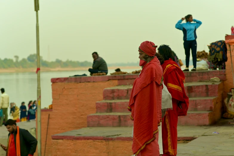 a man and a woman with red dresses are looking at a lake