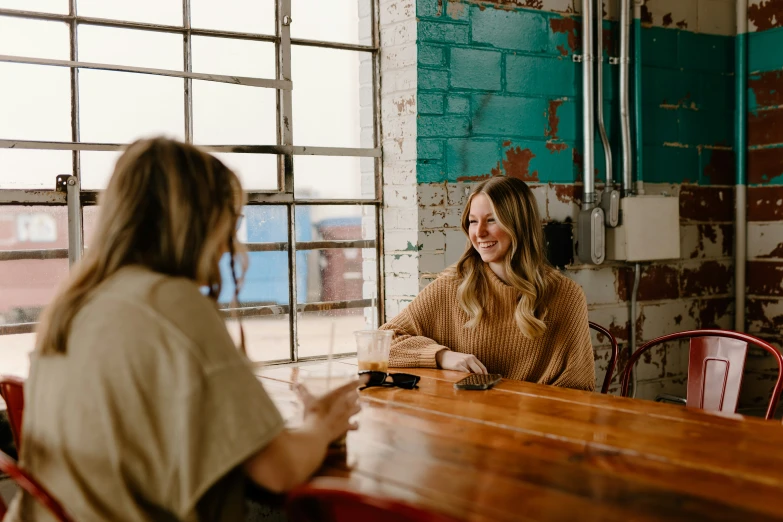 two women talking at a table with some windows