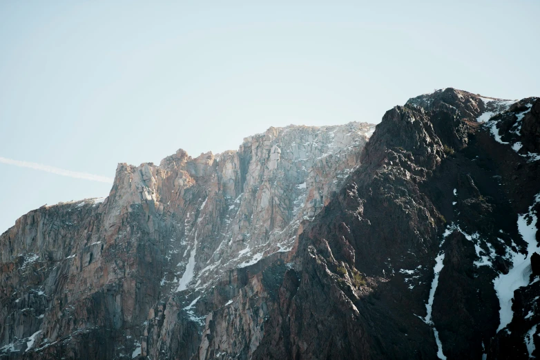 an airplane flying in the sky over the side of a mountain