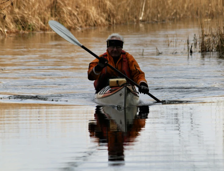 an older man paddles his boat in the water