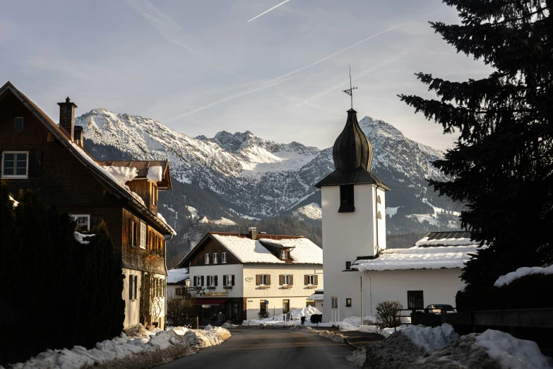 a village street with houses on both sides and mountains behind