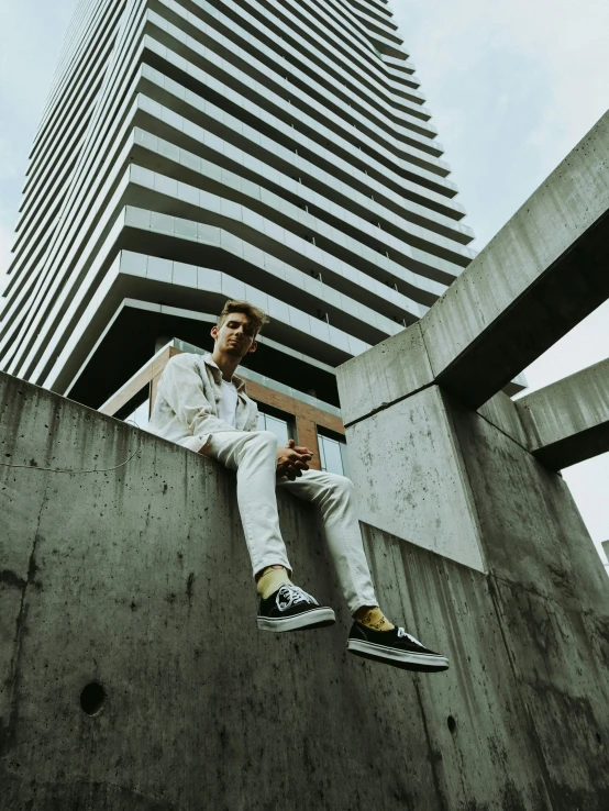 a man with yellow and white sneakers sitting on a cement block