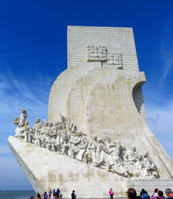 tourists taking pographs near a sculpture by the ocean