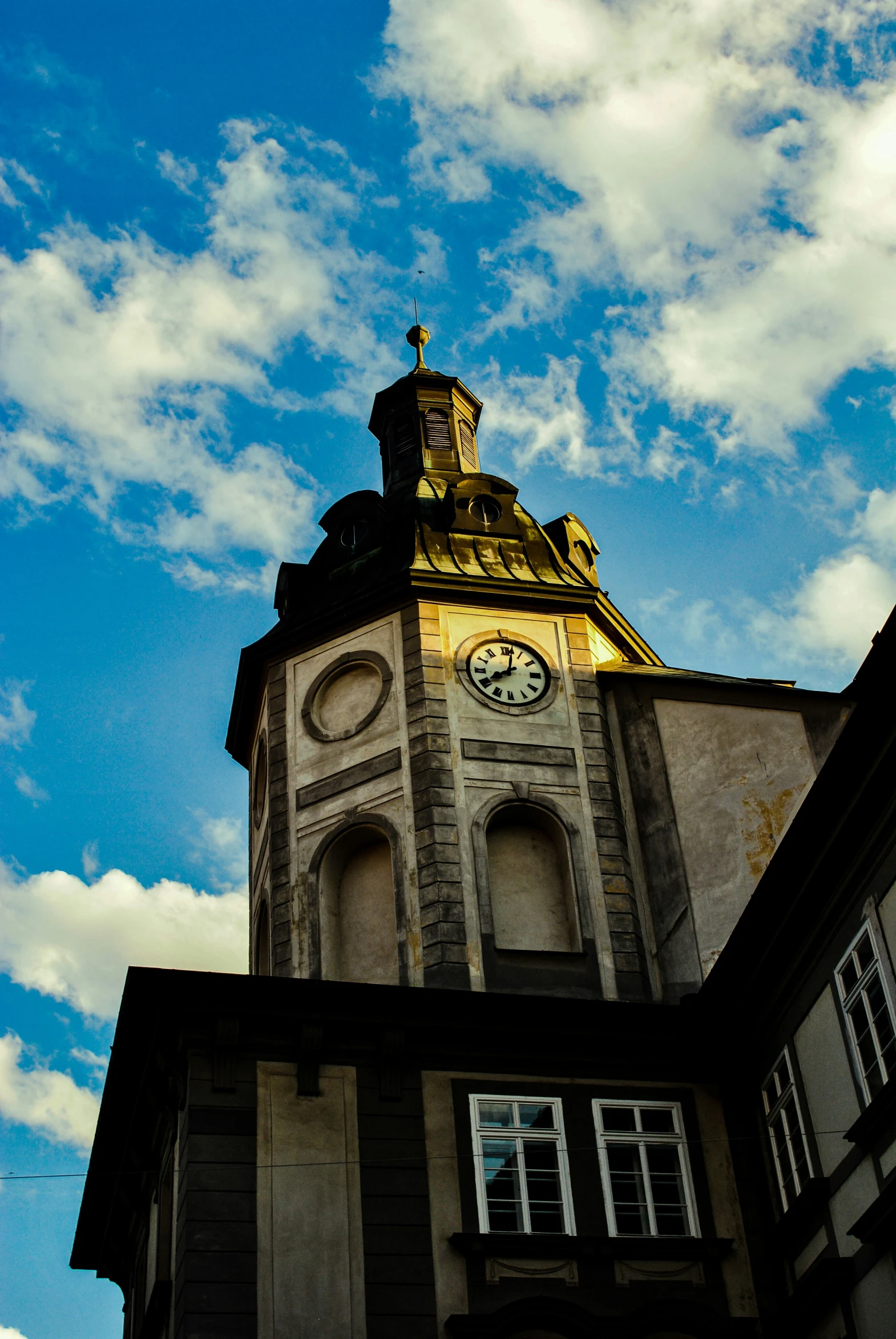 a tall clock tower with a yellow dome and weather vane