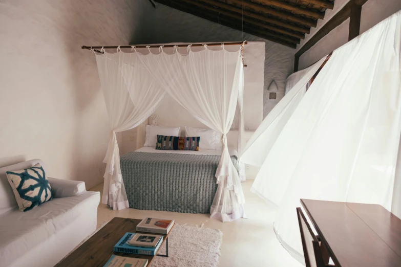 a room is furnished with a white bed, couch and a coffee table