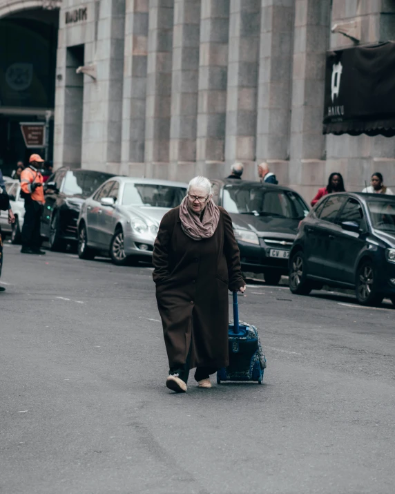 a woman carrying a suitcase down a street