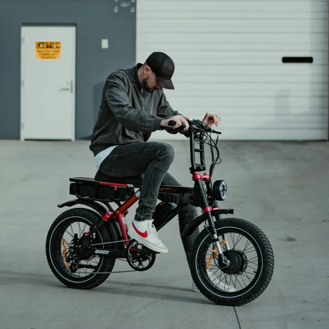 a man riding a black bike next to a garage