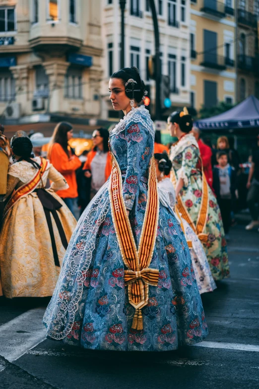 a lady in a long dress walking in the street