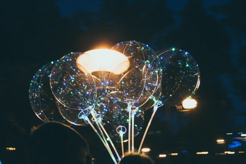 a group of people are looking at some lit up balloons