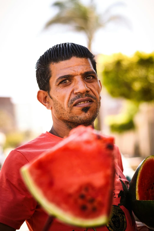 a man who is standing near some watermelon