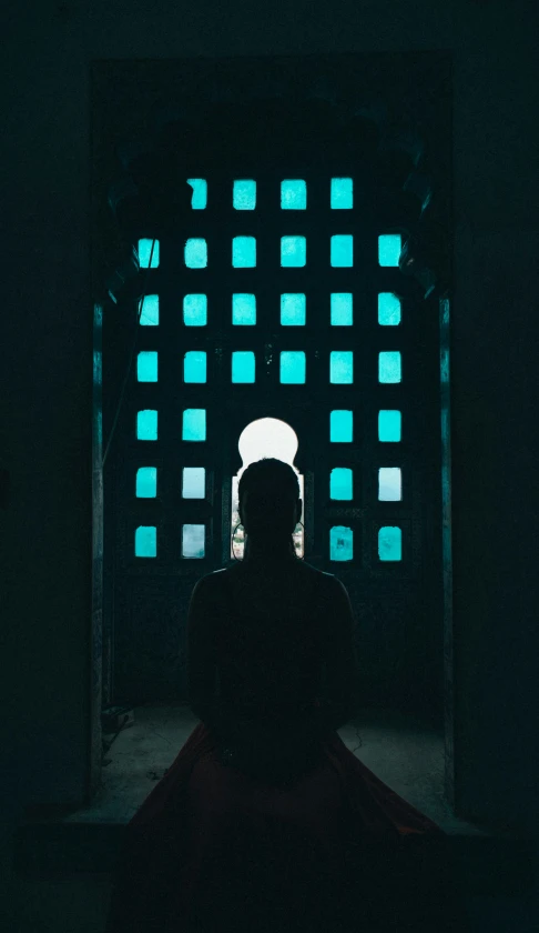 a man is sitting in front of a window with blue glass squares