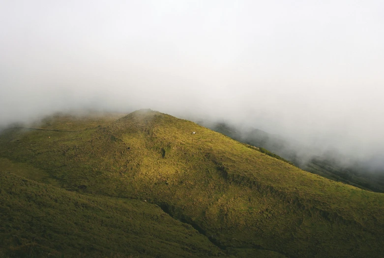 a mountain with a fog filled sky and low lying vegetation