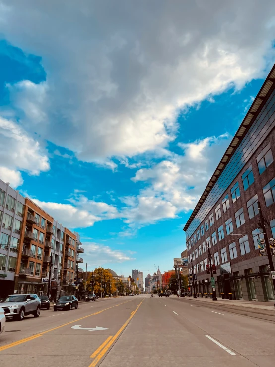 a road lined with parked cars under some clouds