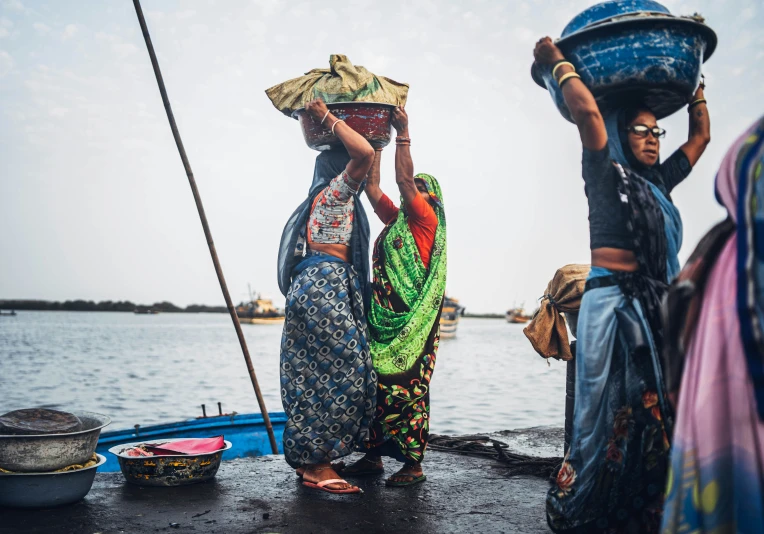 women are standing next to the ocean wearing colorful outfits