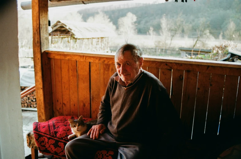 the man is sitting with a cat by himself