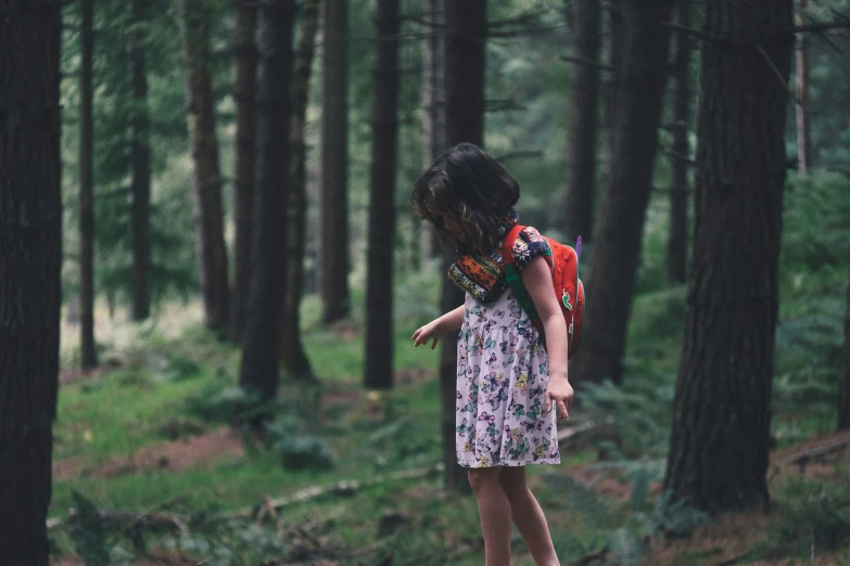 young woman with backpack standing in forest looking for direction
