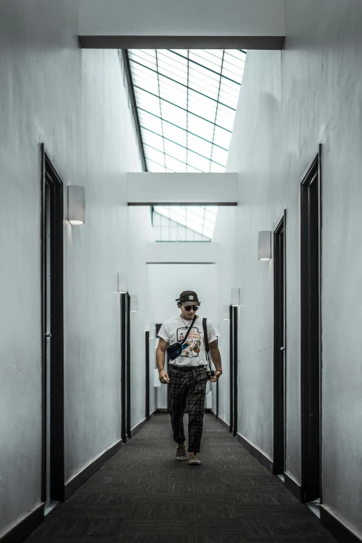 a man walking through a hallway next to a glass ceiling