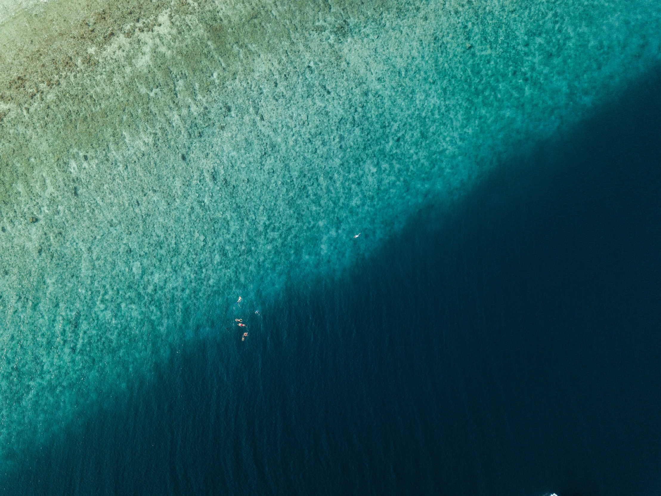 two people ride in the water as a wave breaks