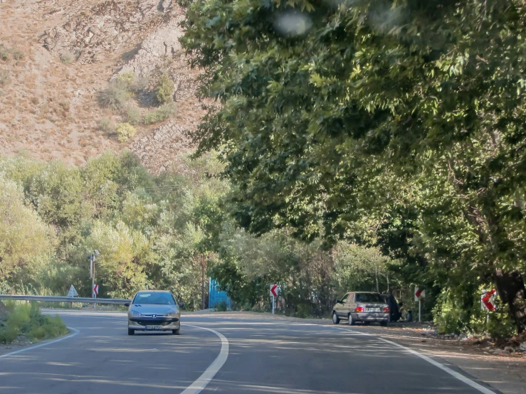 a street with trees on the side and a blue car