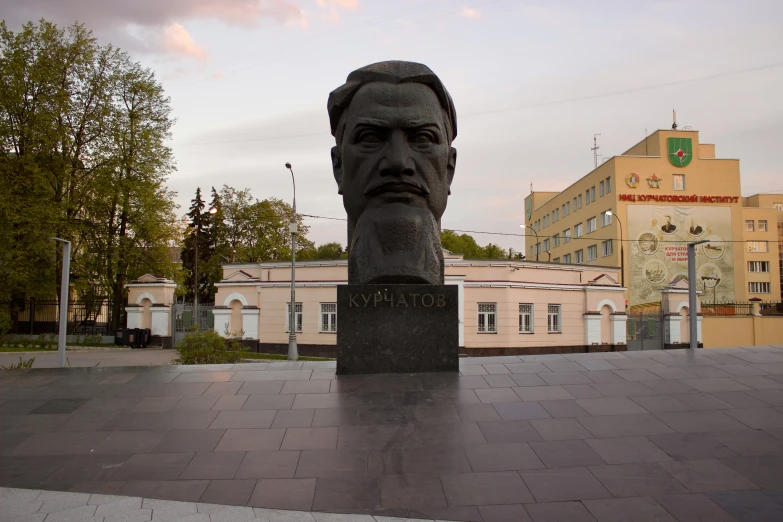 a sculpture of a man's head on a city square