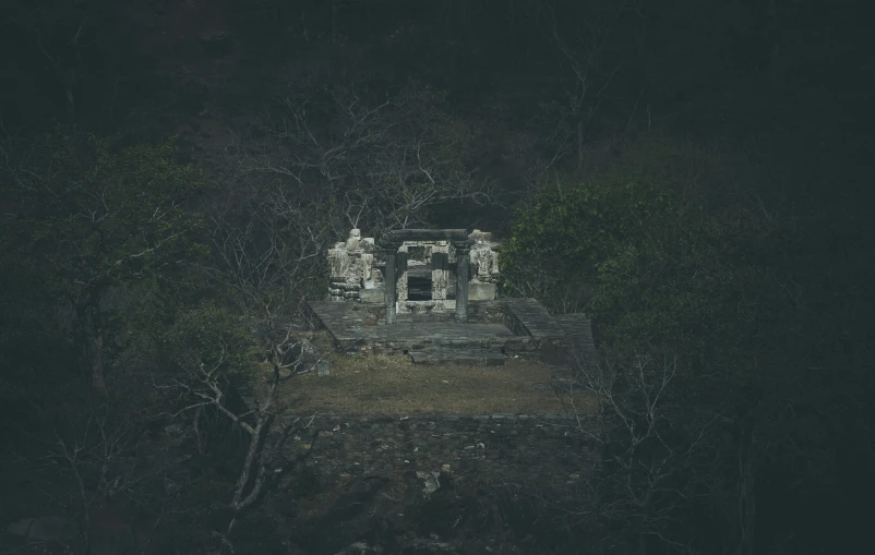 an abandoned building sits among the trees and dark skies