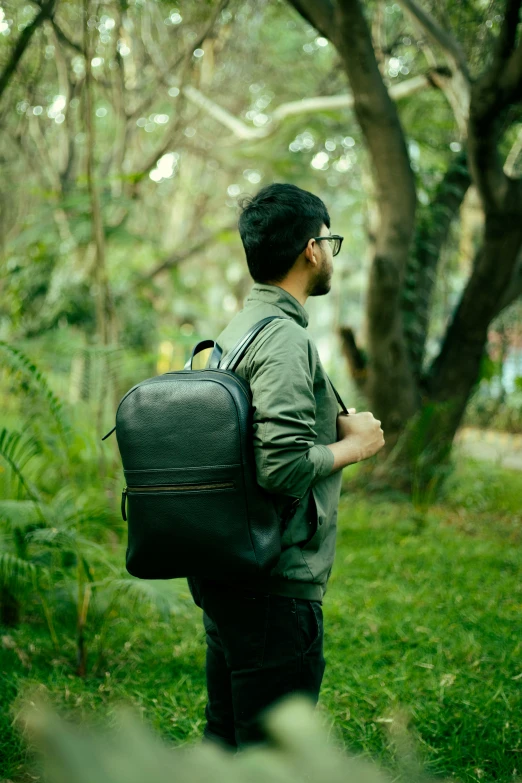 man with backpack walking through woods on green grass