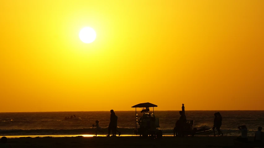 people gathered at a beach in the setting sun