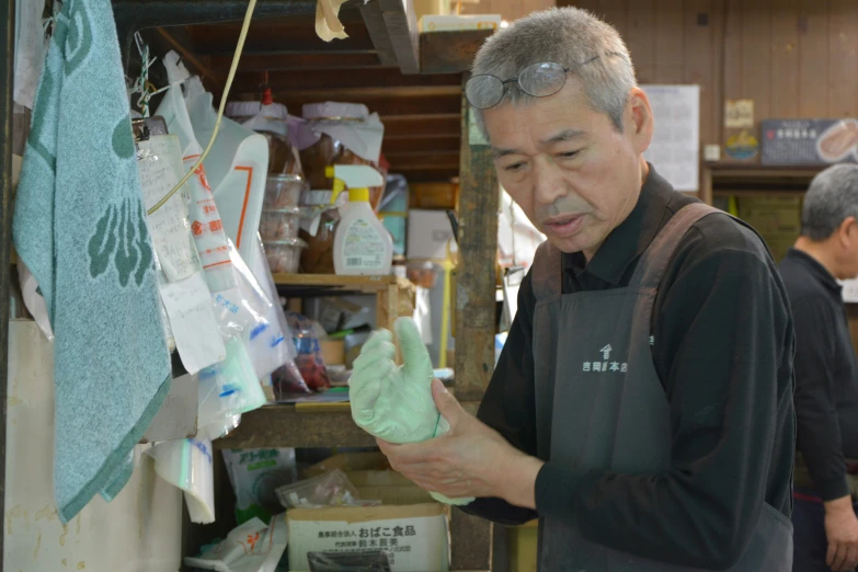 an asian man putting green plastic bags on a bag