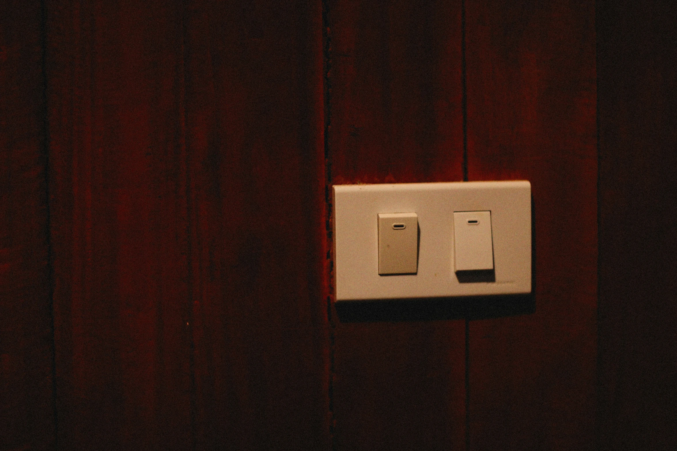 there is a white light switch on a wooden wall