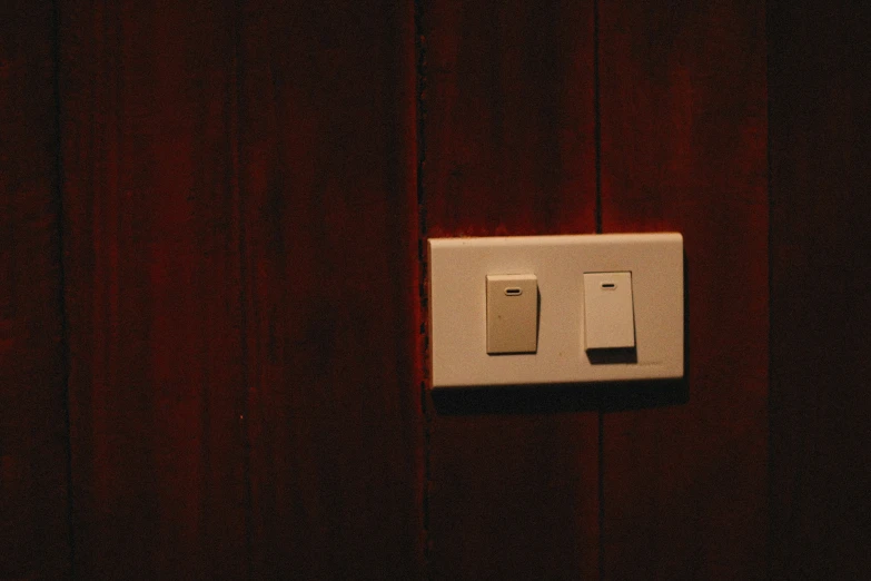 there is a white light switch on a wooden wall