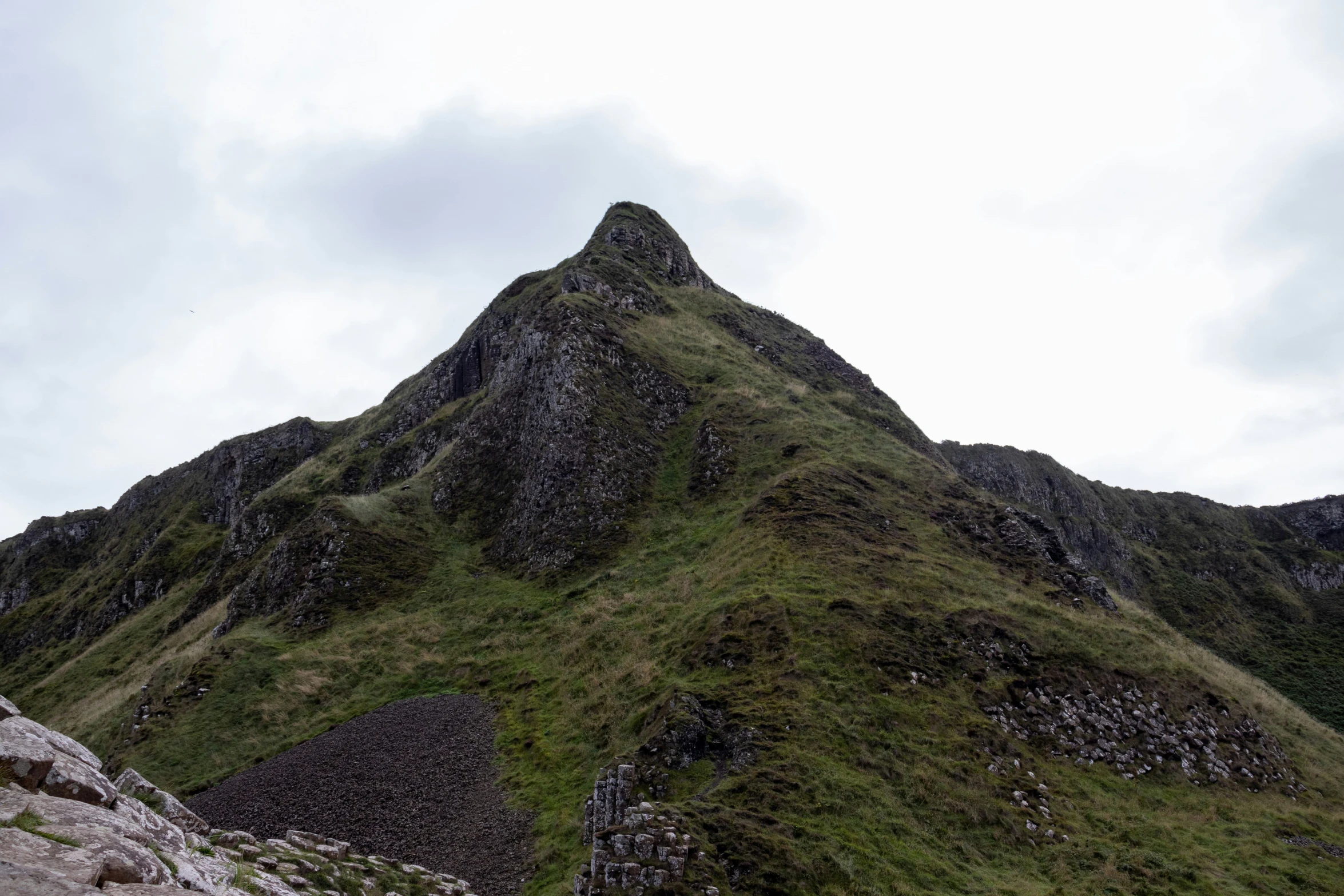 the grassy mountain range is up against the blue sky