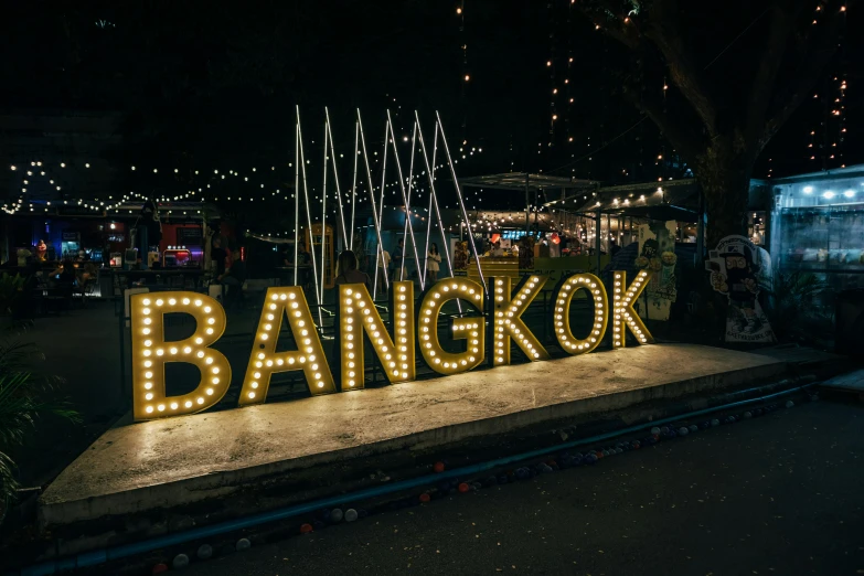 the lighted sign says bangkok next to some lights