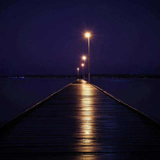 lights shine in the distance along a long dock