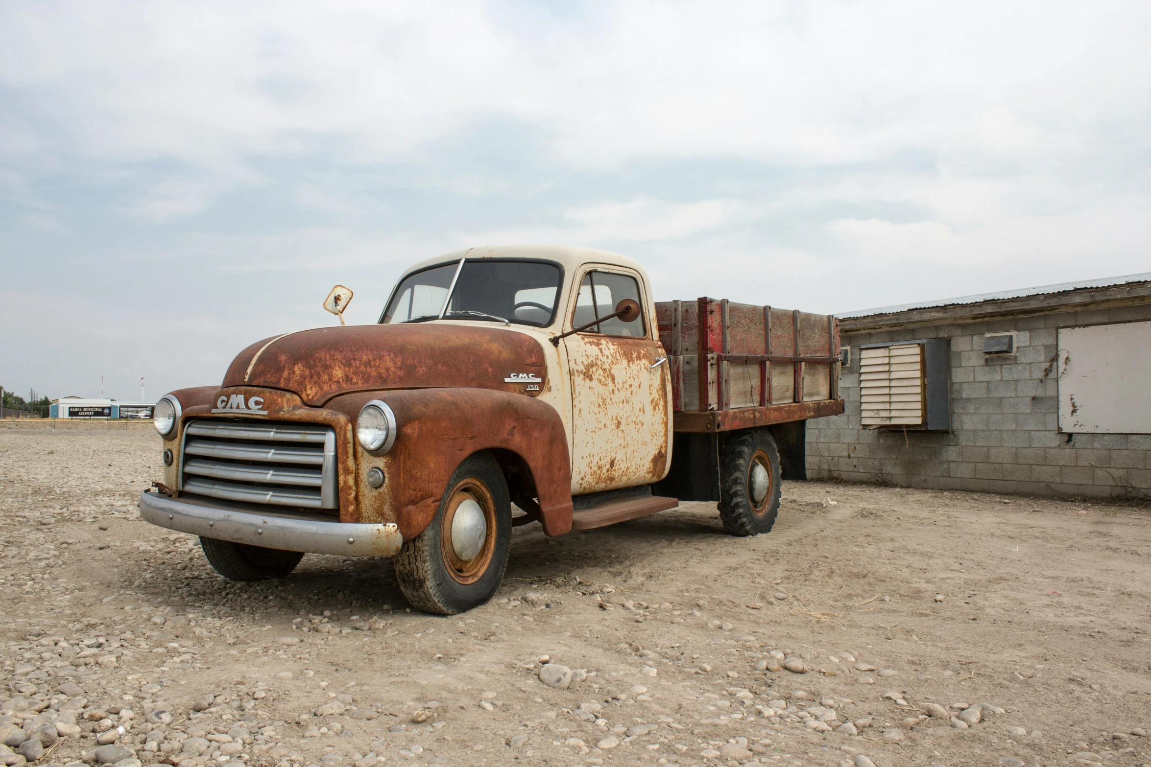 an old truck parked on the beach with no wheels