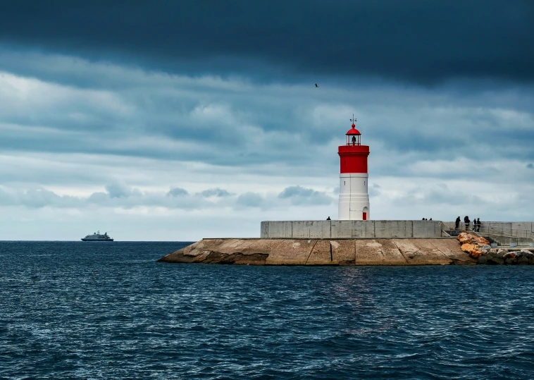 a lighthouse is on top of a small breakwater wall