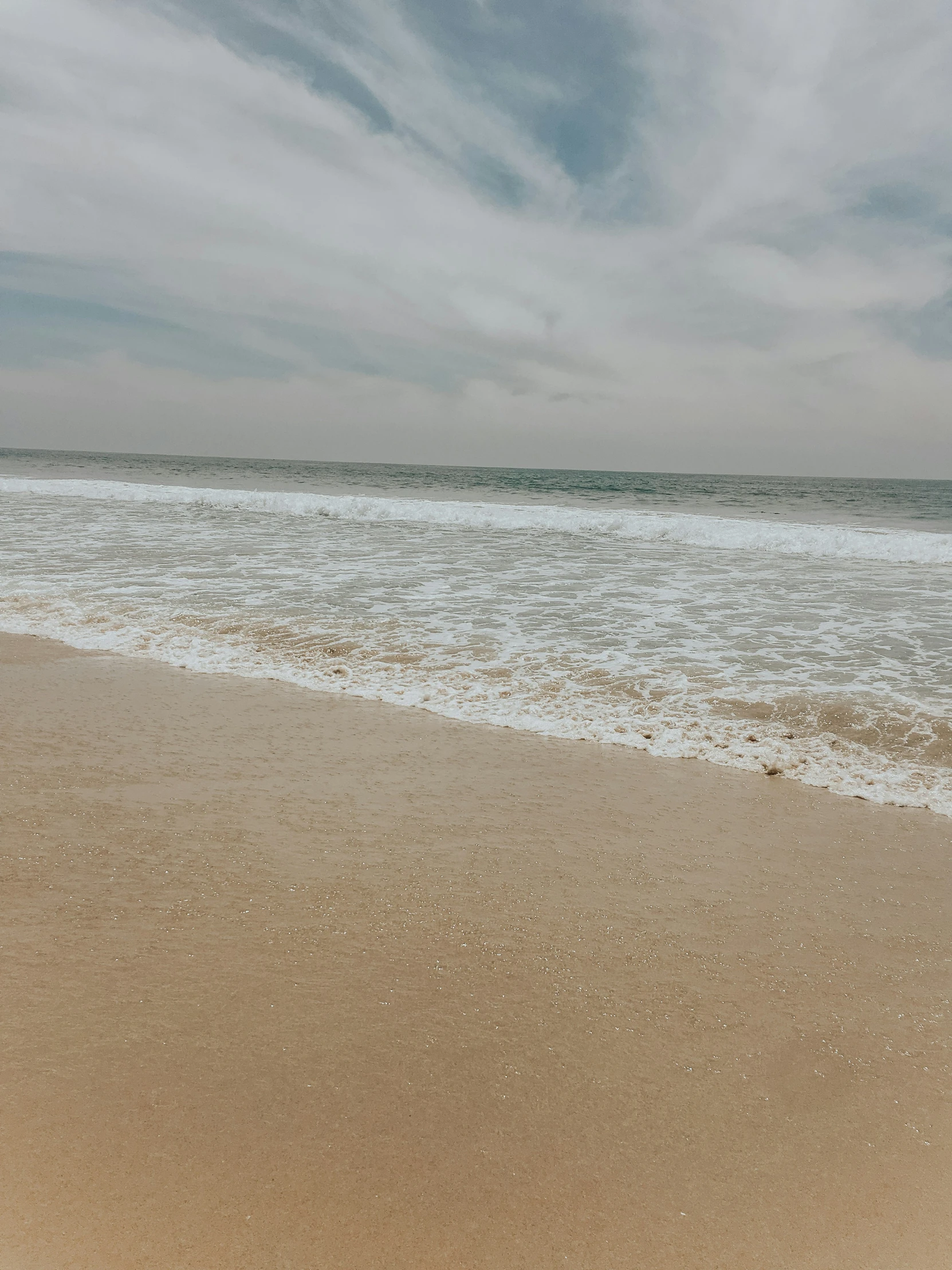 an empty white sand beach on the ocean