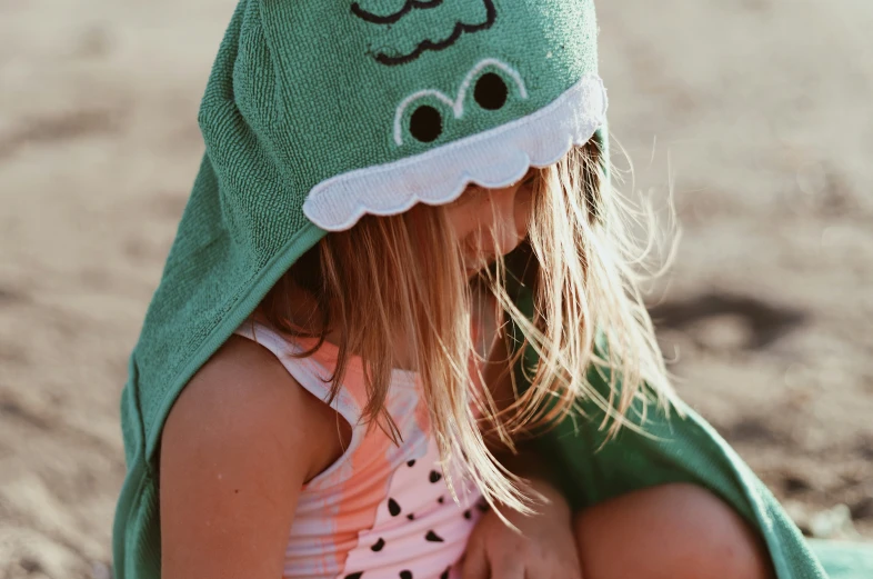 a small girl is wearing a green hat