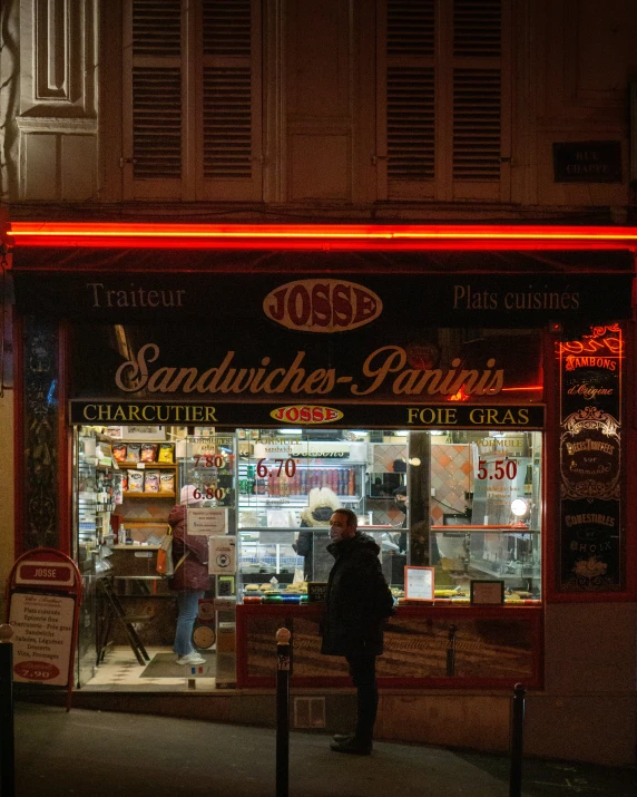 a store with red neon signs and the front windows lit up
