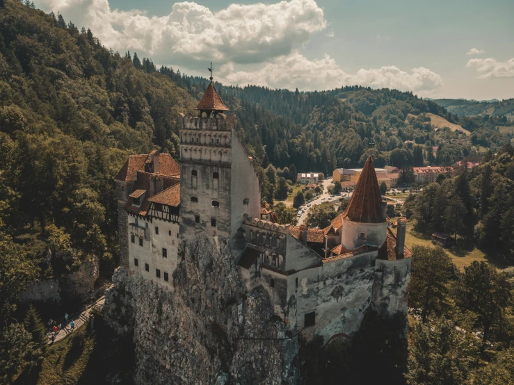 a castle with mountains in the background and clouds in the sky