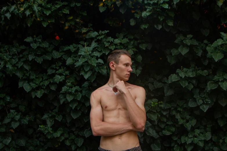 a shirtless man brushing his teeth in front of plants
