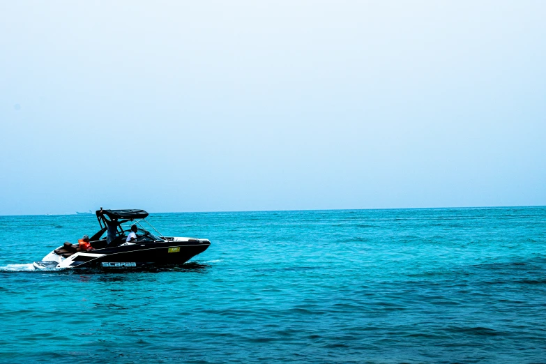 a black boat on the water with blue skies above