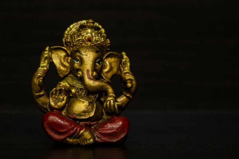 an elephant statue on a dark surface with a red bow around it